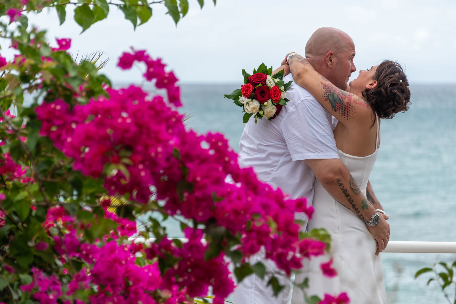Les mariés s’enlacent parmi les fleurs face à la mer